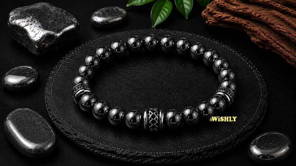 Hematite bracelet with polished metallic grey gemstone beads displayed alongside natural Hematite stones on a dark textured slate surface.